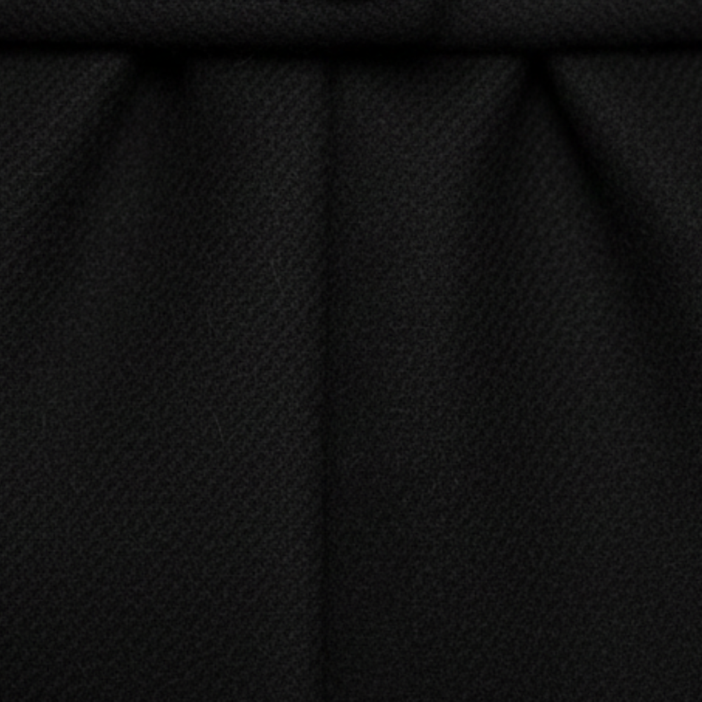 A woman in a long, tailored coat with a notched lapel, standing on a cobblestone street, exuding effortless sophistication.

