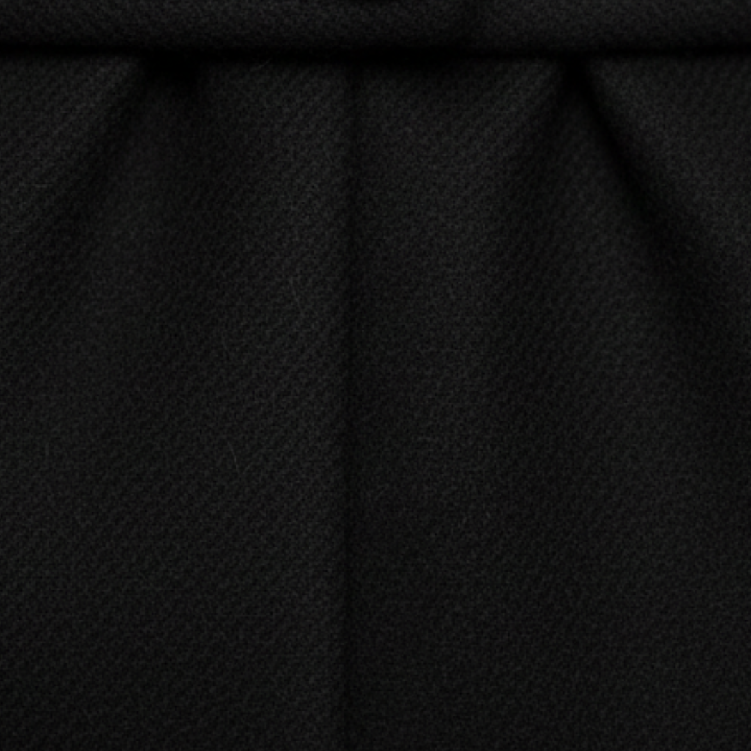 A woman in a long, tailored coat with a notched lapel, standing on a cobblestone street, exuding effortless sophistication.

