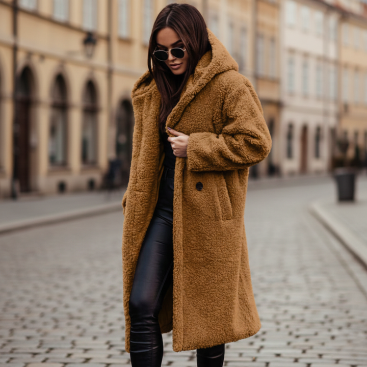 A woman wearing a brown hooded coat and black pants, showcasing a cozy and stylish fall outfit.