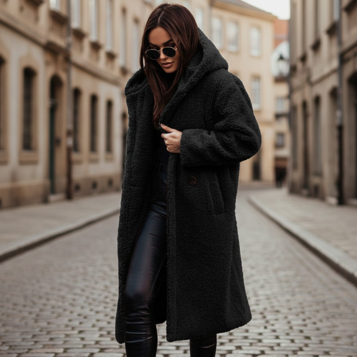 A woman wearing a black hooded coat paired with black pants, showcasing a cozy and stylish fall outfit.