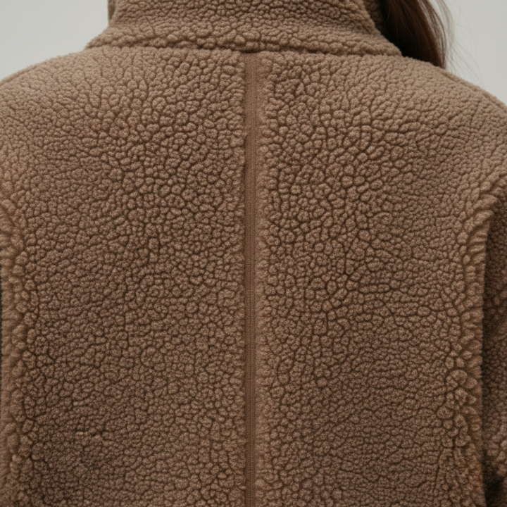 A woman in a brown teddy bear jacket with a high collar and zip front.