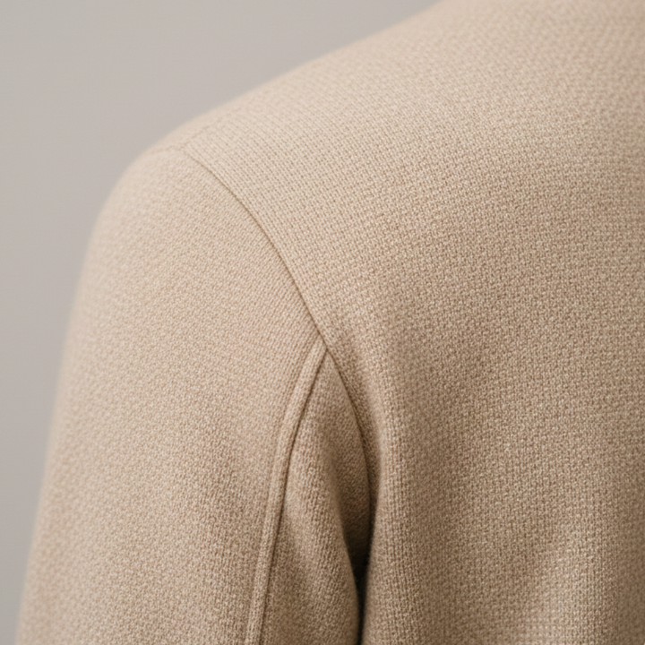 A man wearing a beige jacket stands on a street, featuring a clean silhouette and long sleeves, good for transitional weather.