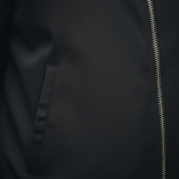  Close-up of a black varsity jacket featuring zippers and striped trims, showcasing a sleek and modern design.