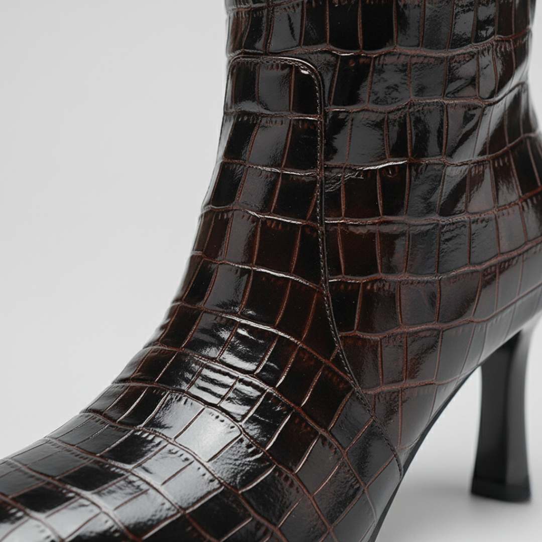 Brown crocodile skin knee-high boots with a slim heel and rounded square toe, good for fall and winter styling.