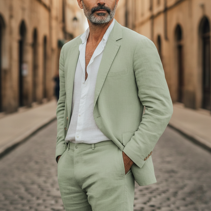 A man in a green linen suit stands on a cobblestone street.