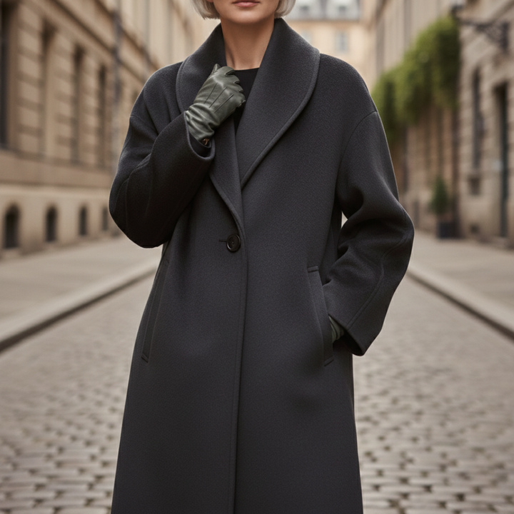 A woman in a blue coat on a cobblestone street, showcasing her outerwear in a refined setting.