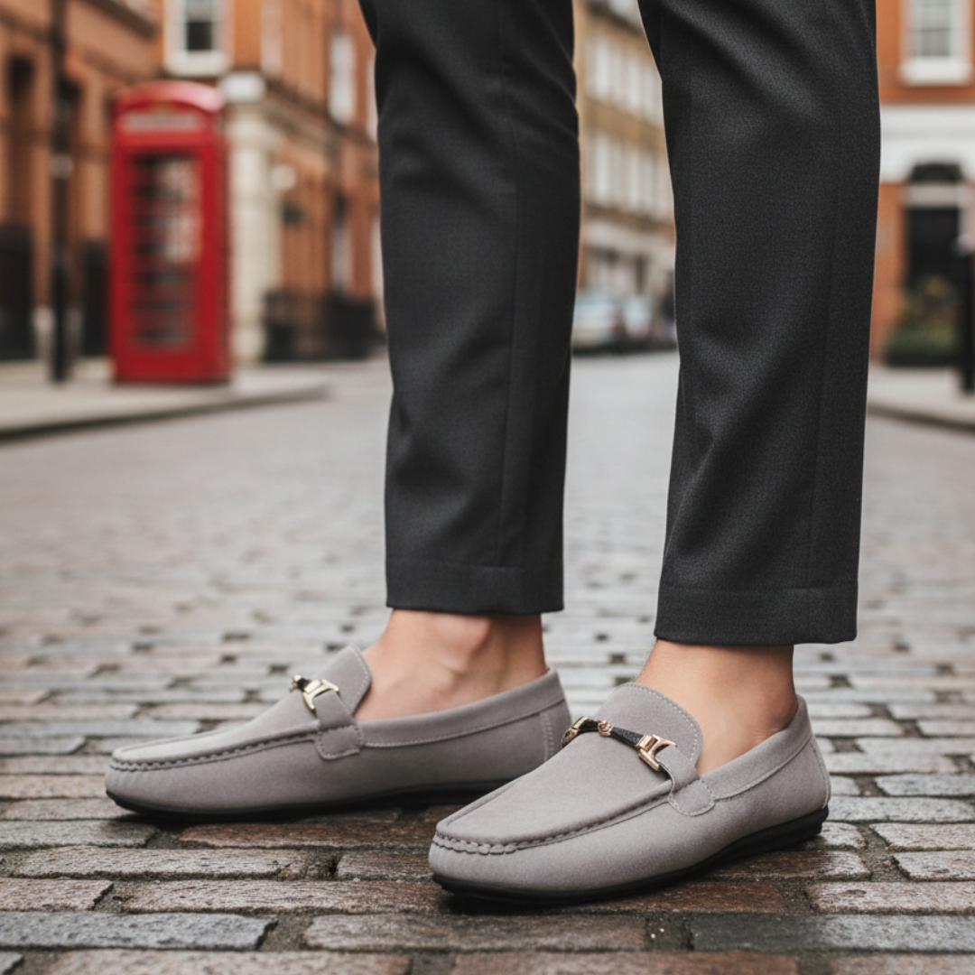 Grey suede loafers featuring a gold buckle, designed for comfort and style, suitable for casual and semi-formal occasions.