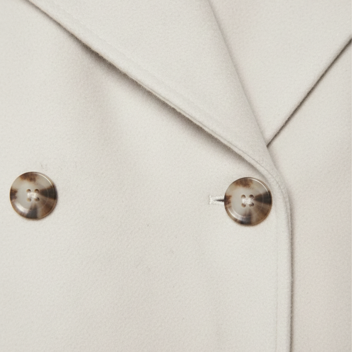 White cropped double-breasted jacket with structured lapels, made from polyester (faux wool), ideal for fall and spring layering.
