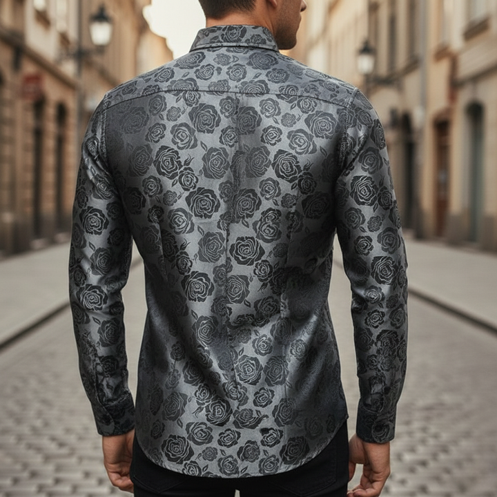 A man wearing a black and silver paisley shirt, showcasing a sophisticated and polished style for evening events.

