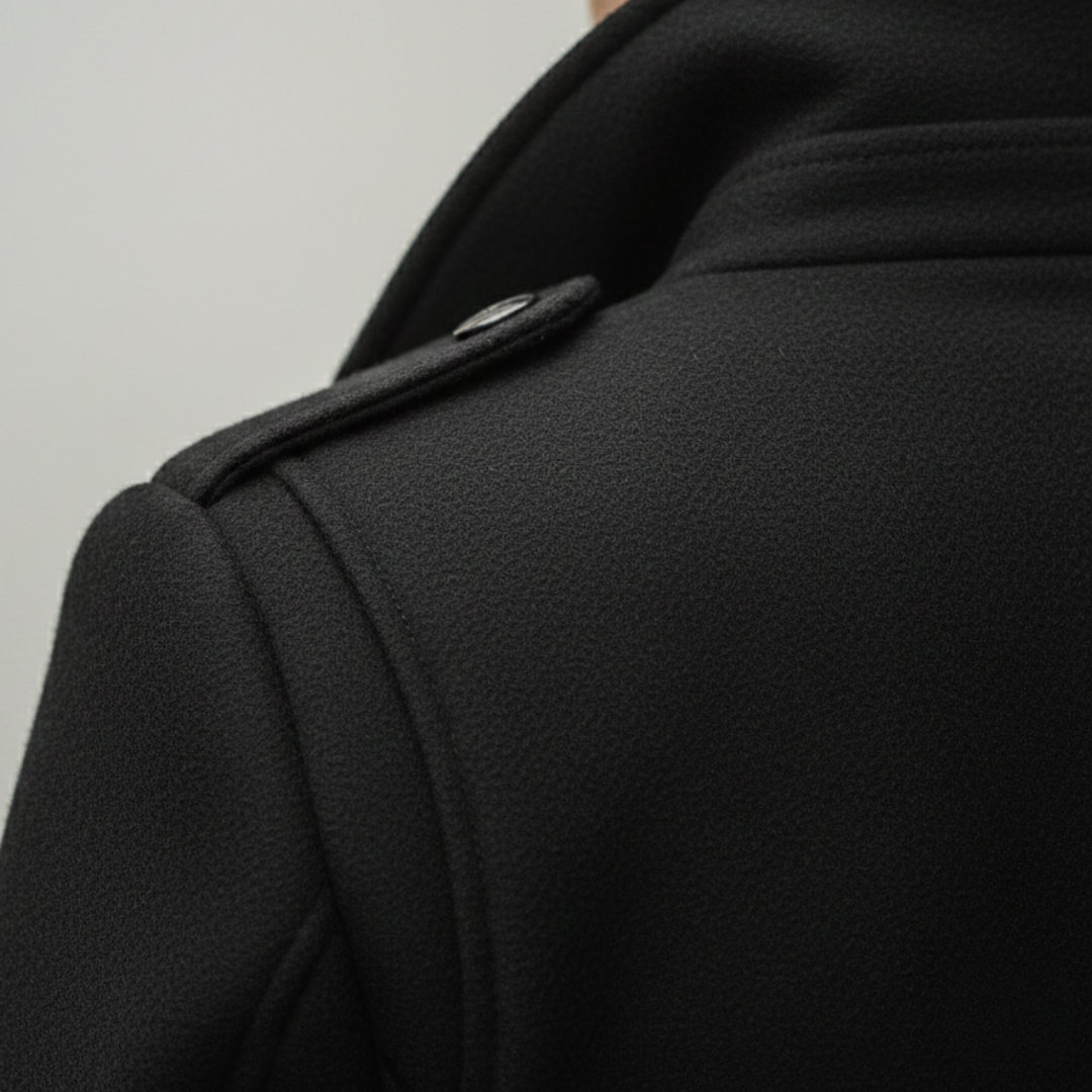Close-up back details look of a black mid-length wool coat featuring a hood, turn-down collar, and long sleeves.