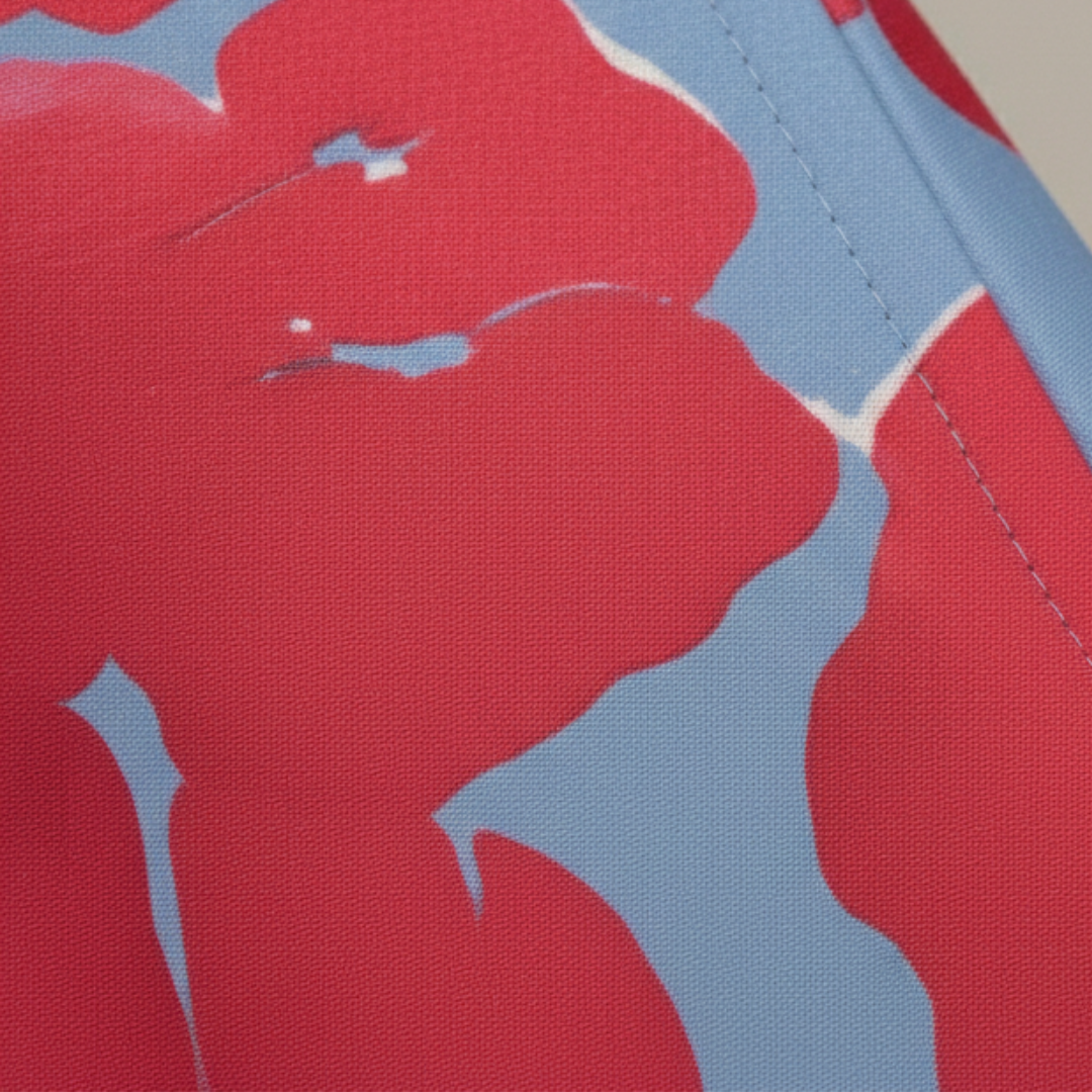 A woman wearing a maxi dress with a red and blue floral design, showcasing a wrap bodice and three-quarter sleeves.