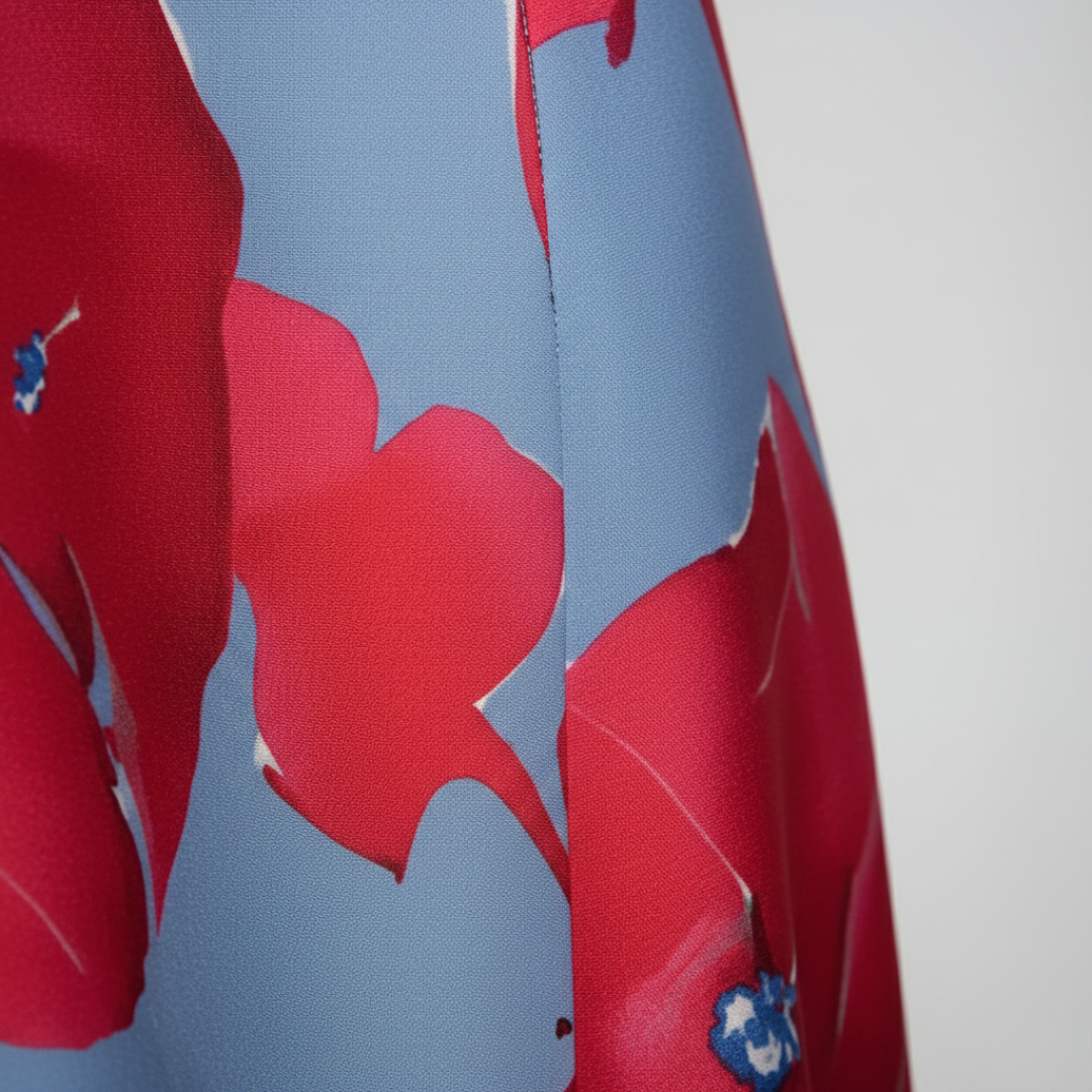 A woman wearing a maxi dress with a red and blue floral design, showcasing a wrap bodice and three-quarter sleeves.