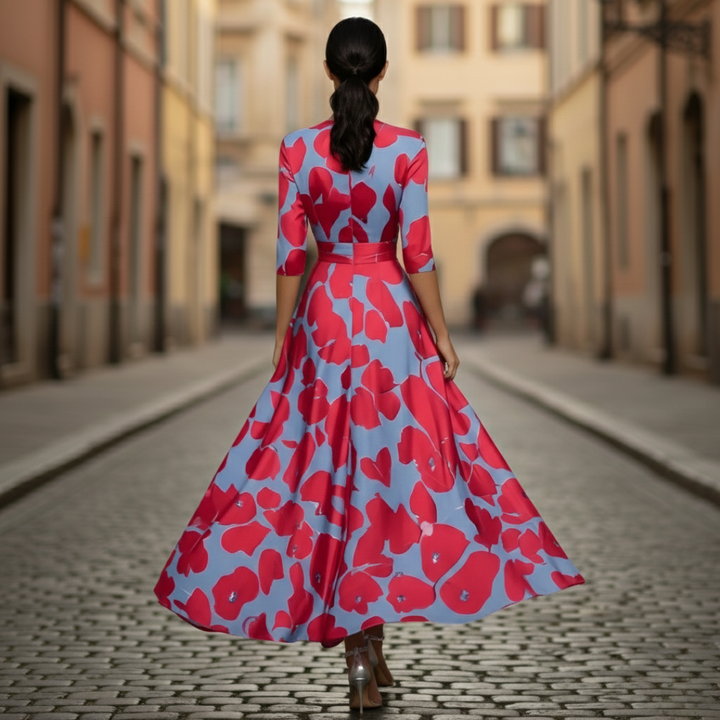 A woman wearing a maxi dress with a red and blue floral design, showcasing a wrap bodice and three-quarter sleeves.