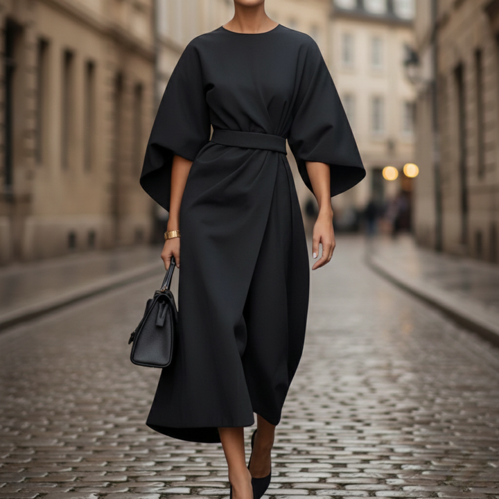 A woman wearing a black midi dress with wide sleeves.