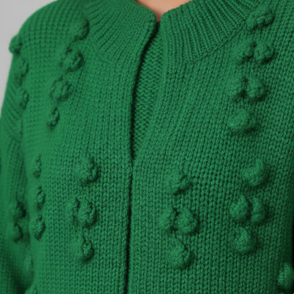 Close-up details of a green cardigan, embodying with a soft, open-front duster for fall and winter.