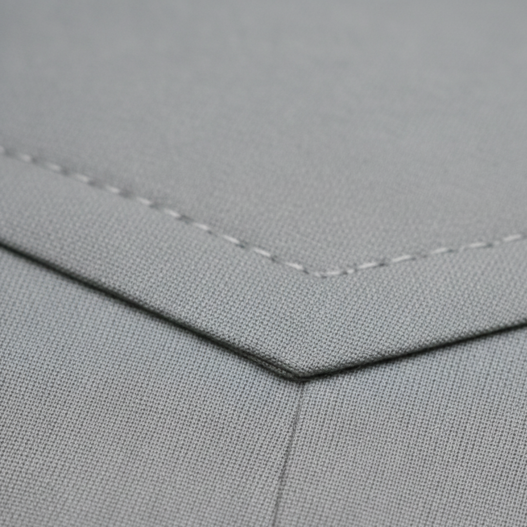 Close-up details of the  tailored grey suit stands confidently on a cobblestone street.