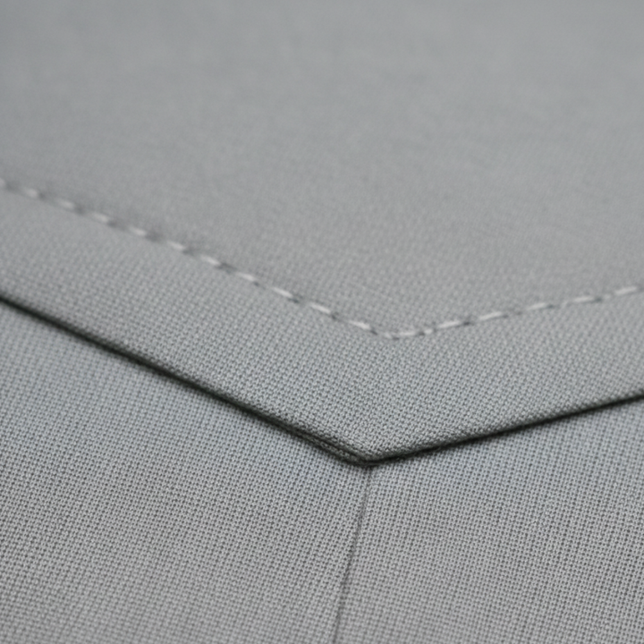 Close-up details of the  tailored grey suit stands confidently on a cobblestone street.