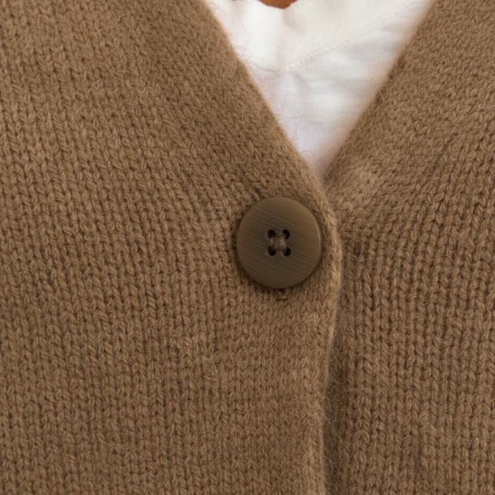  A woman in a beige cardigan sweater, with button-front, showcasing the long sleeves and V-neck, good for fall and spring layering.