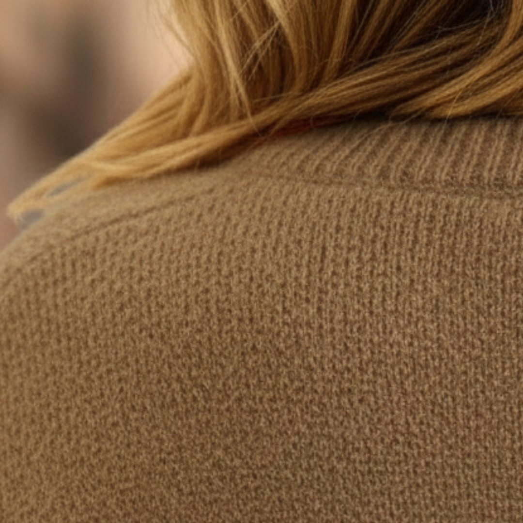 A woman in a beige cardigan sweater, with button-front, showcasing the long sleeves and V-neck, good for fall and spring layering.