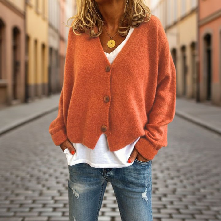  A woman in orange cardigan sweater, with button-front, showcasing the long sleeves and V-neck, good for fall and spring layering.