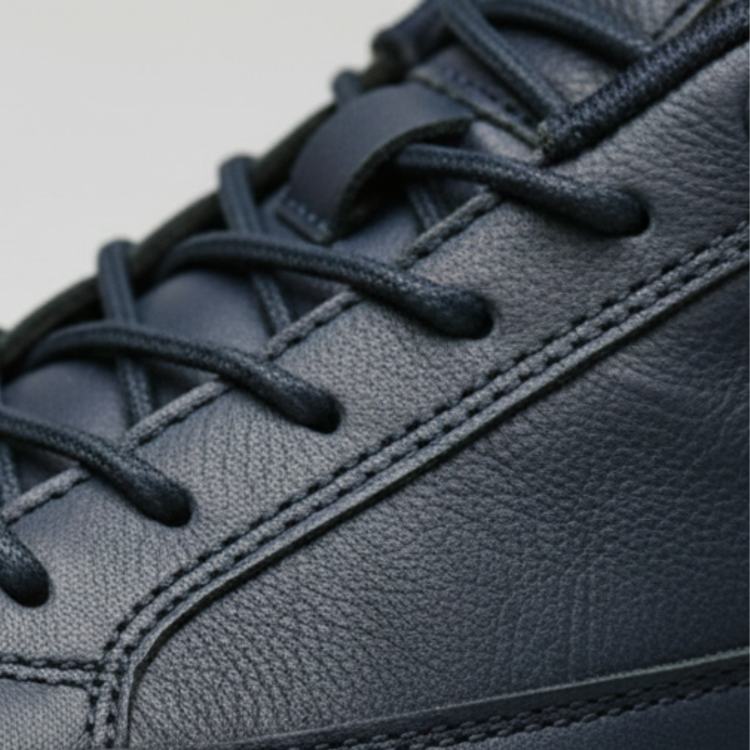 Men's navy leather sneakers with a lace-up design, cushioned sole, and rounded toe.