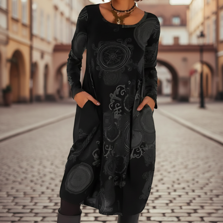 A woman models a midi dress with a  abstract patterns, good for transitional seasons.