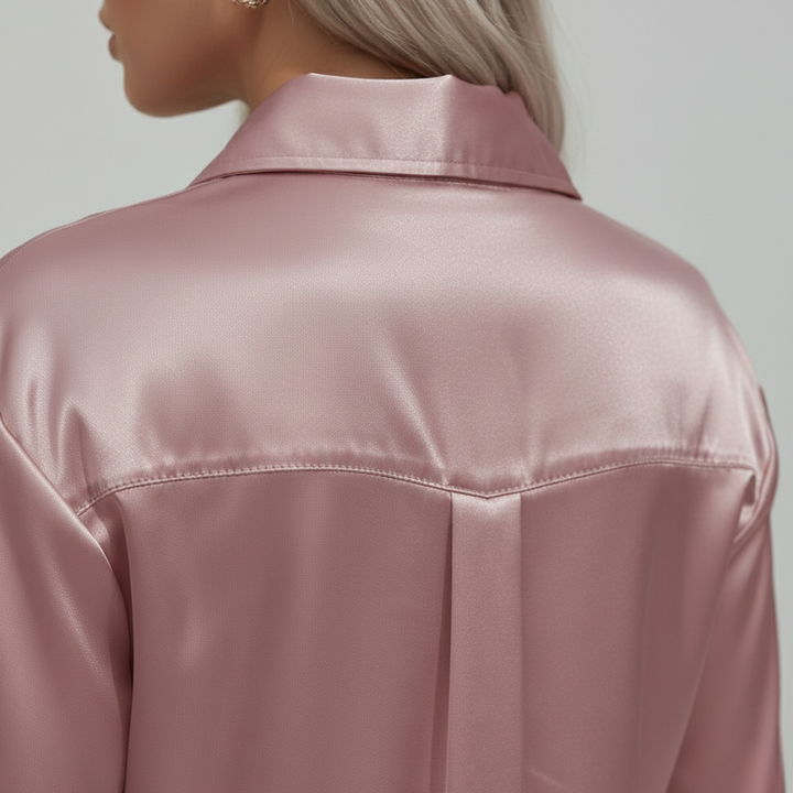 Close-up back details look of a pink satin blouse with a collared neckline and long sleeves