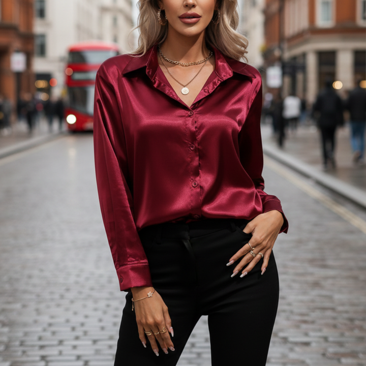 a woman wearing a red satin blouse with a collared neckline and long sleeves, paired with black pants for a chic look.
