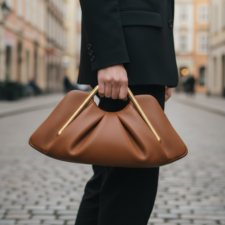 Small brown clutch bag with a gold geometric handle, featuring a pleated design and semi-rigid structure for elegant occasions.