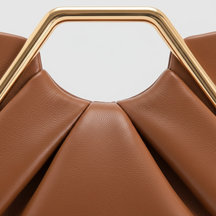 Close-up details of brown clutch bag with a gold geometric handle, featuring a pleated design and semi-rigid structure for elegant occasions.